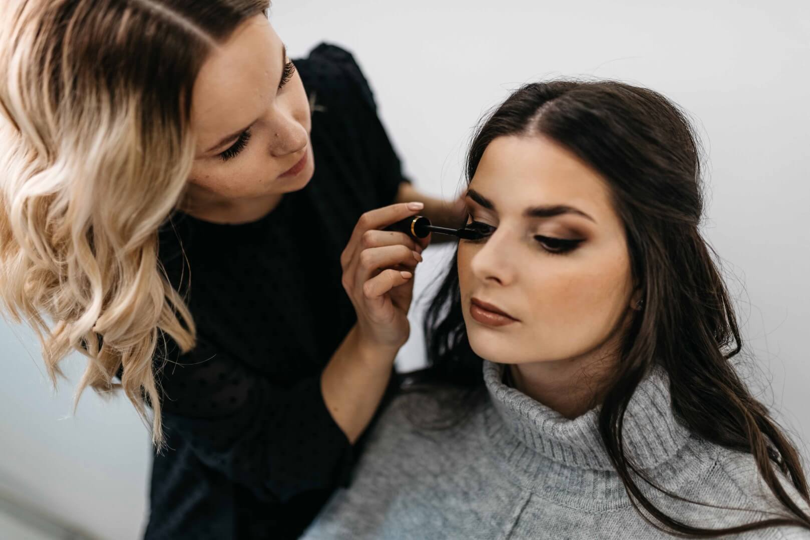 Vizažistka stranki nanaša maskaro.